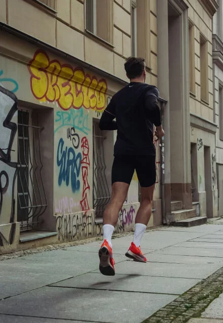 Pessoa correndo em uma rua de cidade, praticando corrida urbana. Imagem para site de fitness ou design de web site.